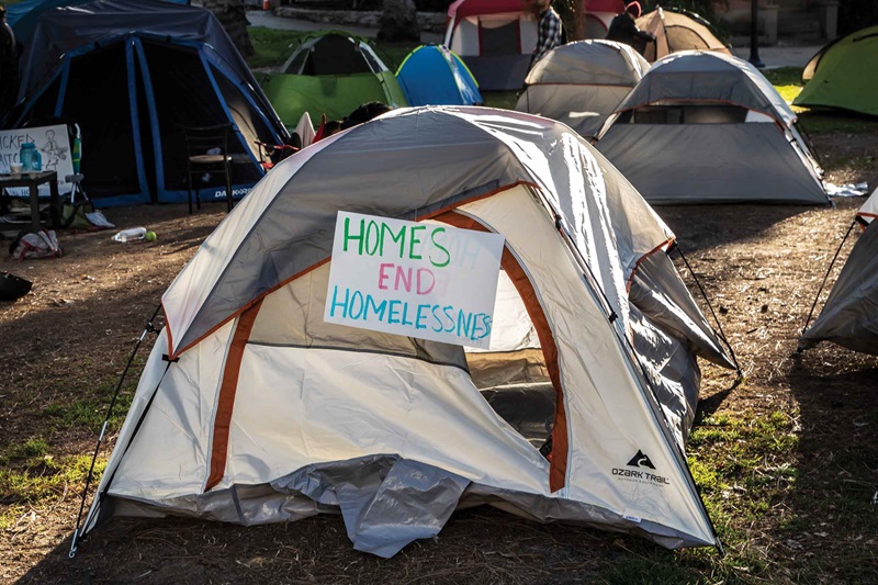 Text with "HOMES END HOMELESSNESS" sign