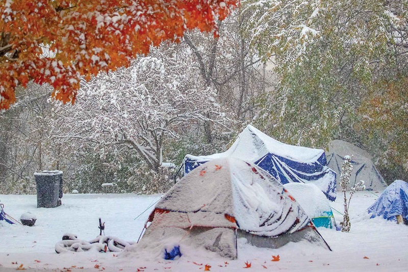 Homeless tents in a park all covered in snow