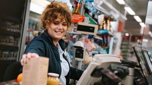 A curly-haired female cashier scanning customer's items at a grocery store