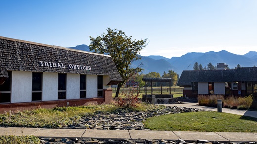 Exterior of the tribal offices of the Confederated Salish and Kootenai Tribes of the Flathead Reservation in Montana, with mountains visible in the background.