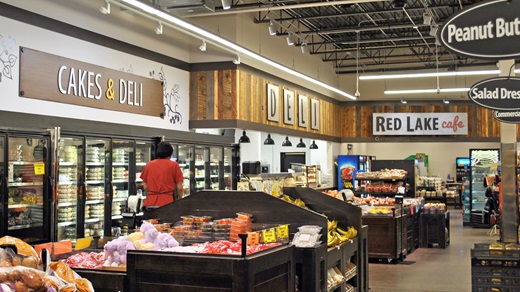 Interior of the Red Lake Trading Post grocery store, with produce and other displays in the foreground and the cake cases, deli counter, and in-store cafe in the background