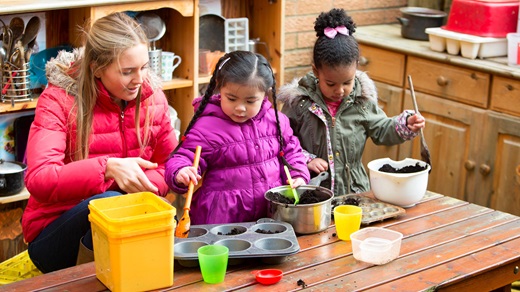 Child care worker and children making mud pies outdoors