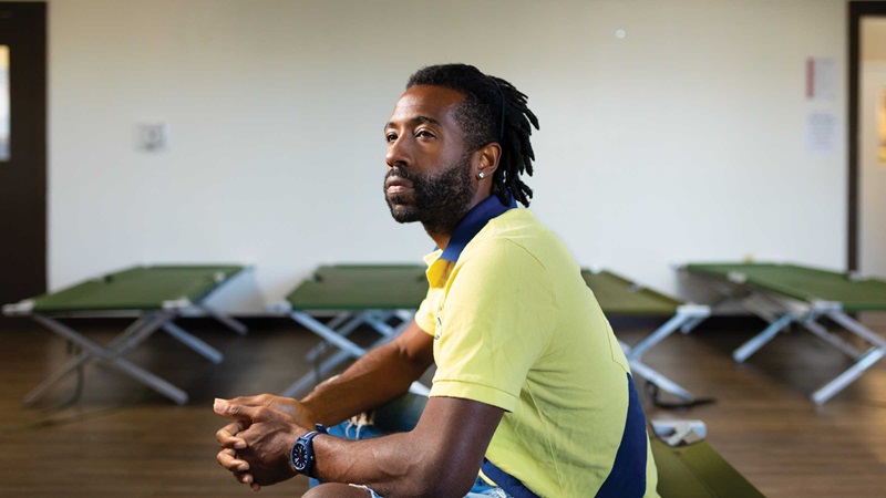 Man sitting in shelter with cots behind