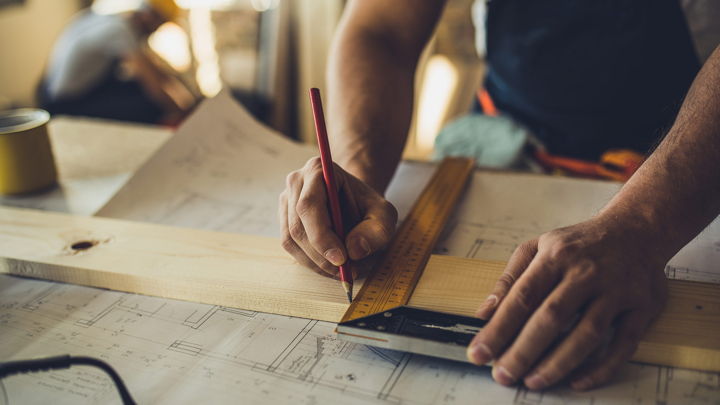 A carpenter measuring and marking a piece of wood