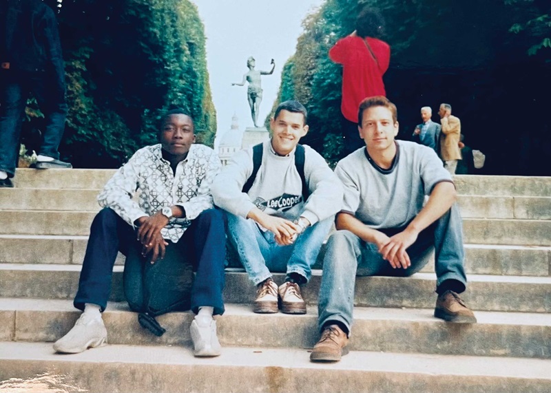 An old photo of Illenin as a student sitting on steps with two other students