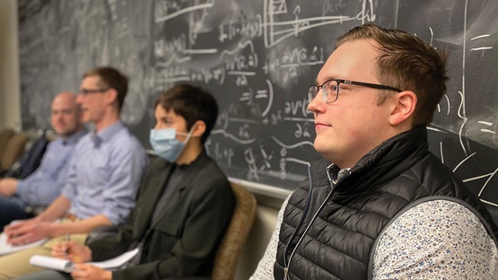 Photo of four people sitting together in front of a blackboard