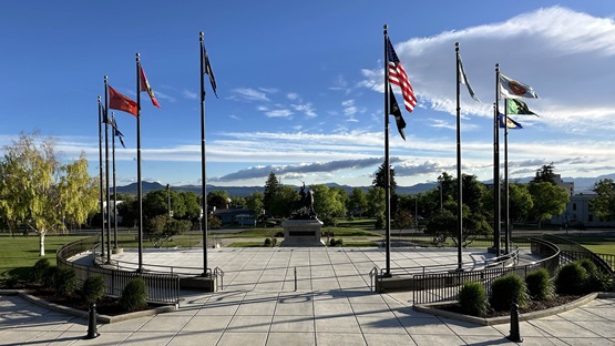 On a sunny day at the Montana State Capitol Tribal Flag Plaza in Helena, flags of the eight federally recognized tribal nations in Montana wave alongside the U.S. and State of Montana flags. 