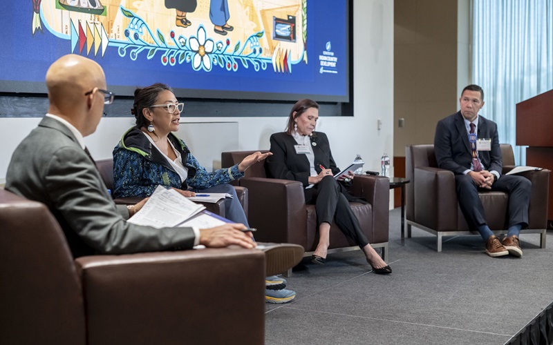 At the Center for Indian Country Development 10th Anniversary and Data Summit event on October 8–9, 2025, four speakers are seated onstage as they participate in a panel discussion. Pictured from left to right are Andy Huff of the Federal Reserve Bank of Minneapolis, Debbie Atuk of Bering Straits Native Corporation Government Services LLC, Mary Mashunkashey of the Office of the Tax Commission for the Muscogee Creek Nation, and Joel Rosette of Rocky Boy Health Center. Atuk is speaking and gesturing as the other panelists listen.