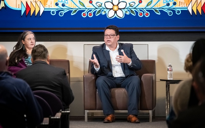 At the Center for Indian Country Development 10th Anniversary and Data Summit event on October 8–9, 2025, Amber Schulz-Oliver of the Affiliated Tribes of Northwest Indians and Cory Blankenship of NAFOA participate in a panel discussion. Both are seated in front of an audience, with Shulz-Oliver at left, listening, and BLankenship in the center, speaking and gesturing.