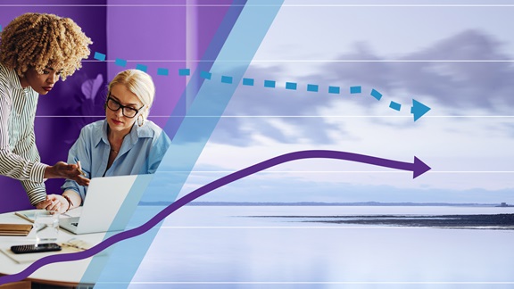 Two female colleagues meeting in an office on the left beside an image of tranquil lake scene with a graph spanning the whole image. 