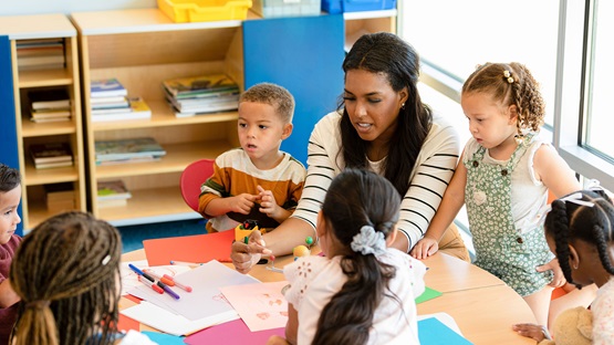 Child care provider working with a group of children at a table