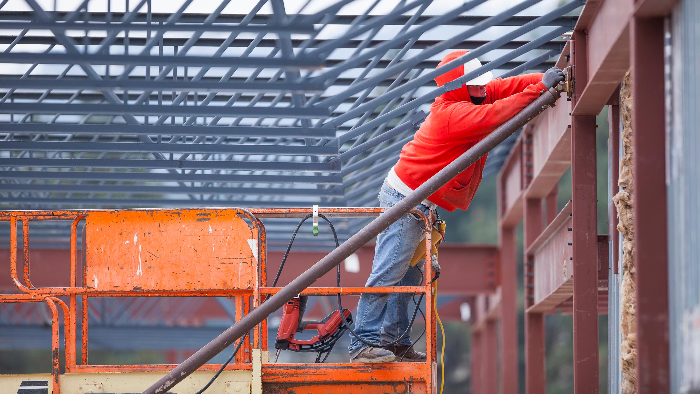 Construction worker welding steel beams at a commercial building site