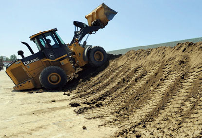 An earth mover packs down a dike as higher crest estimates of the Souris River were announced.