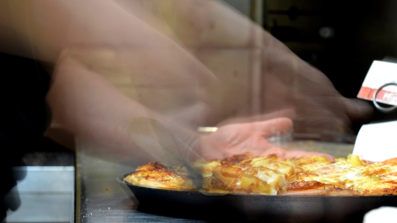 Photo of a restaurant worker cutting a pizza