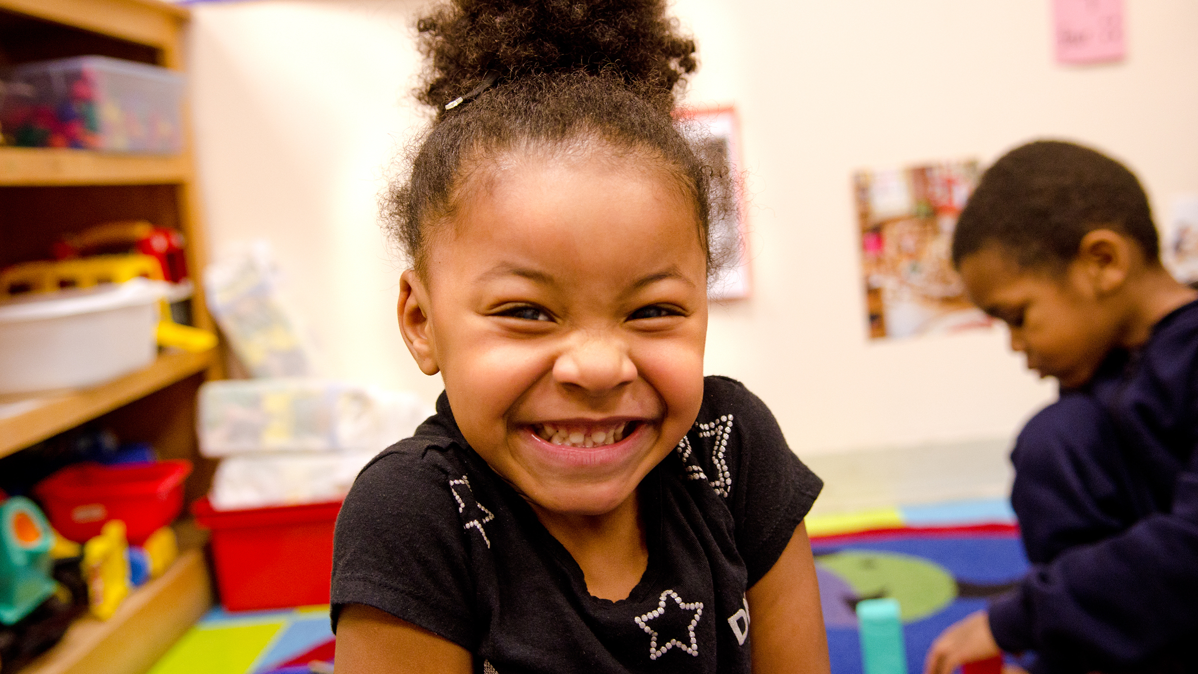 Smiling little girl at Family Partnership child care center in Minneapolis, image for 'Read more: Connections between ECE and the economy' sidebar