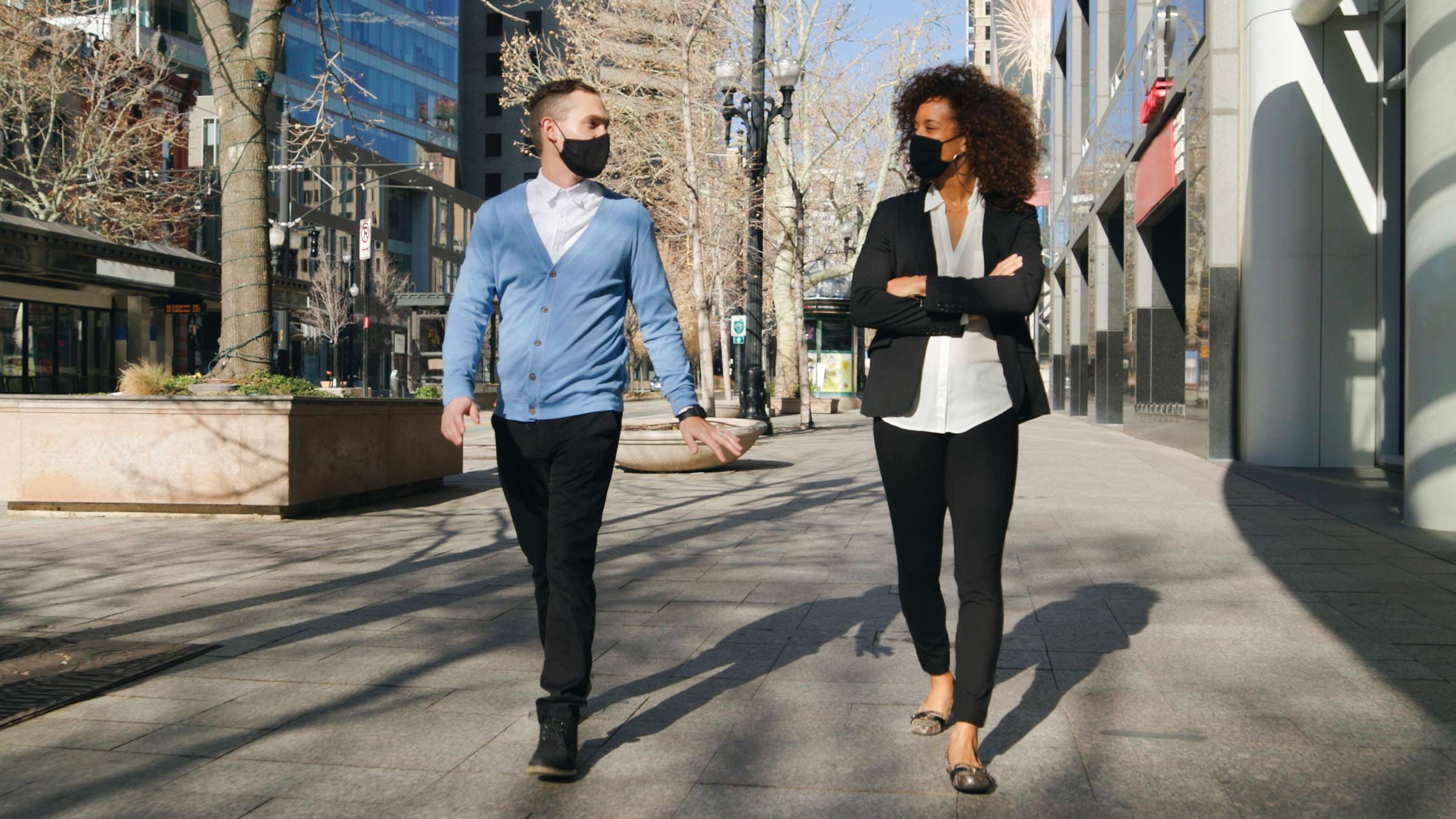 Two people with face masks walking through the city
